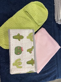 a cactus towel, a pink towel, and a green towel