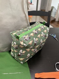 a green zippered pouch with scissors on a table